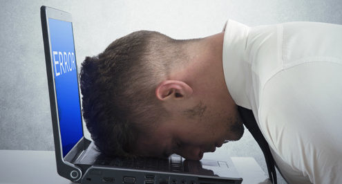 a person banging their head against a computer, symbolic of mediocre IT support
