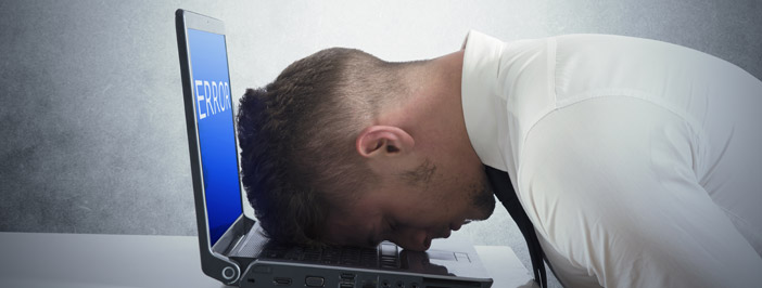 a person banging their head against a computer, symbolic of mediocre IT support