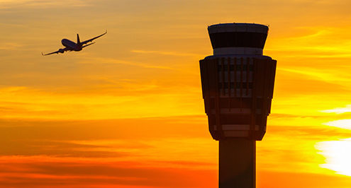 Airplane flying by radar tower.